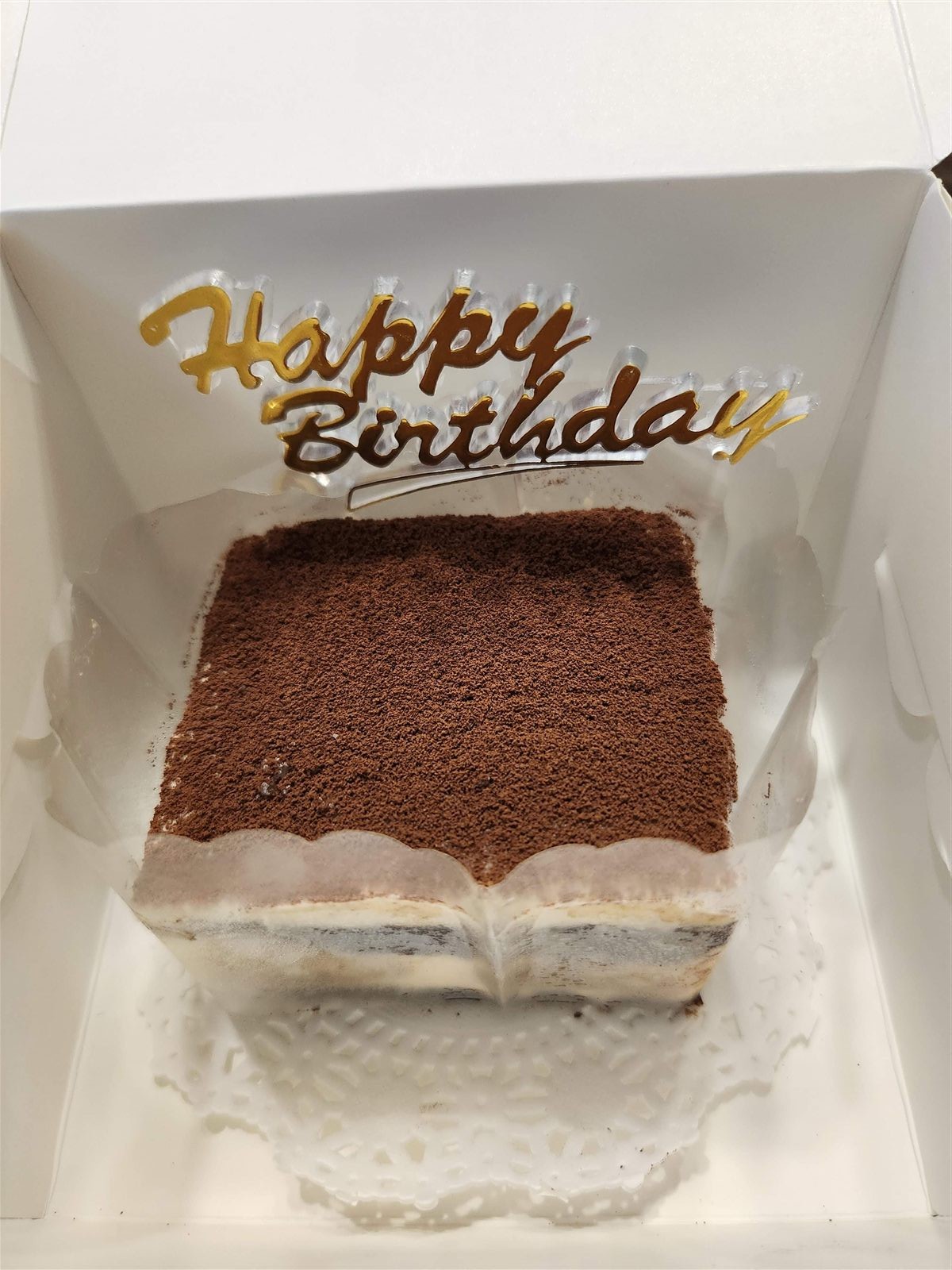 Gluten-free tiramisu cake in a gift box with a Happy Birthday topper